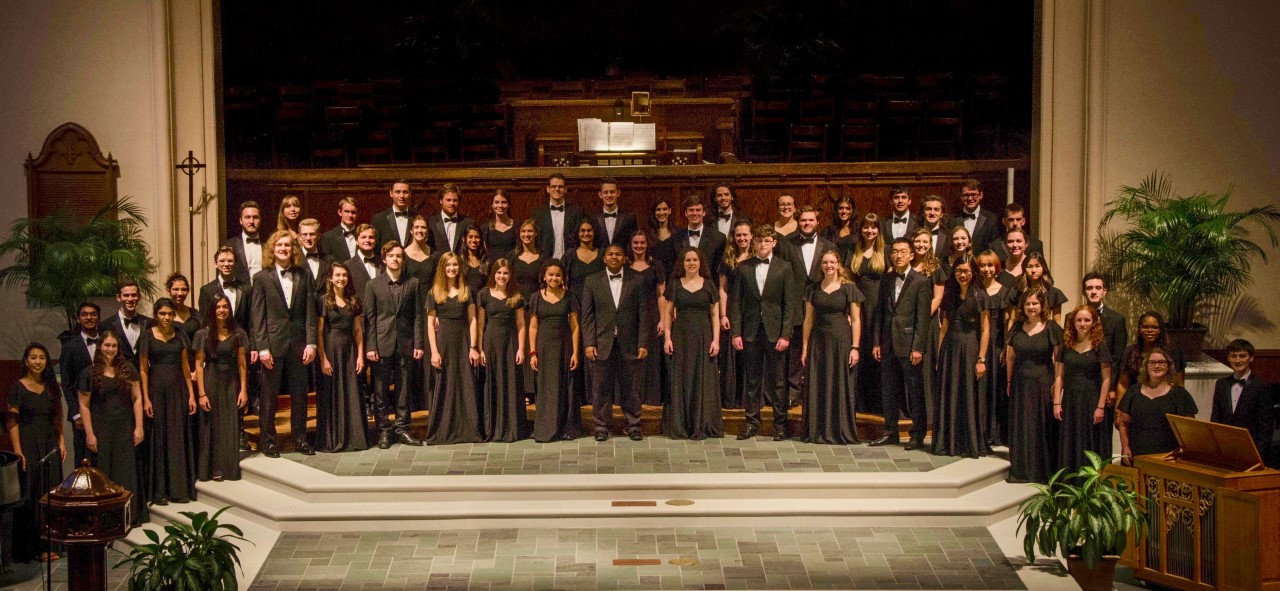 Chamber choir stands for photo in a large auditorium
