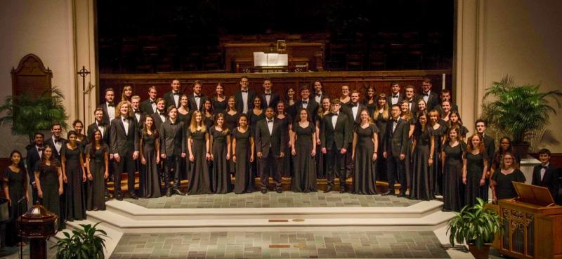 Chamber choir stands for a photo in a large auditorium