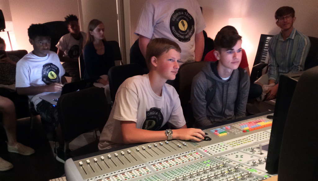 High school students gather around a mixing board