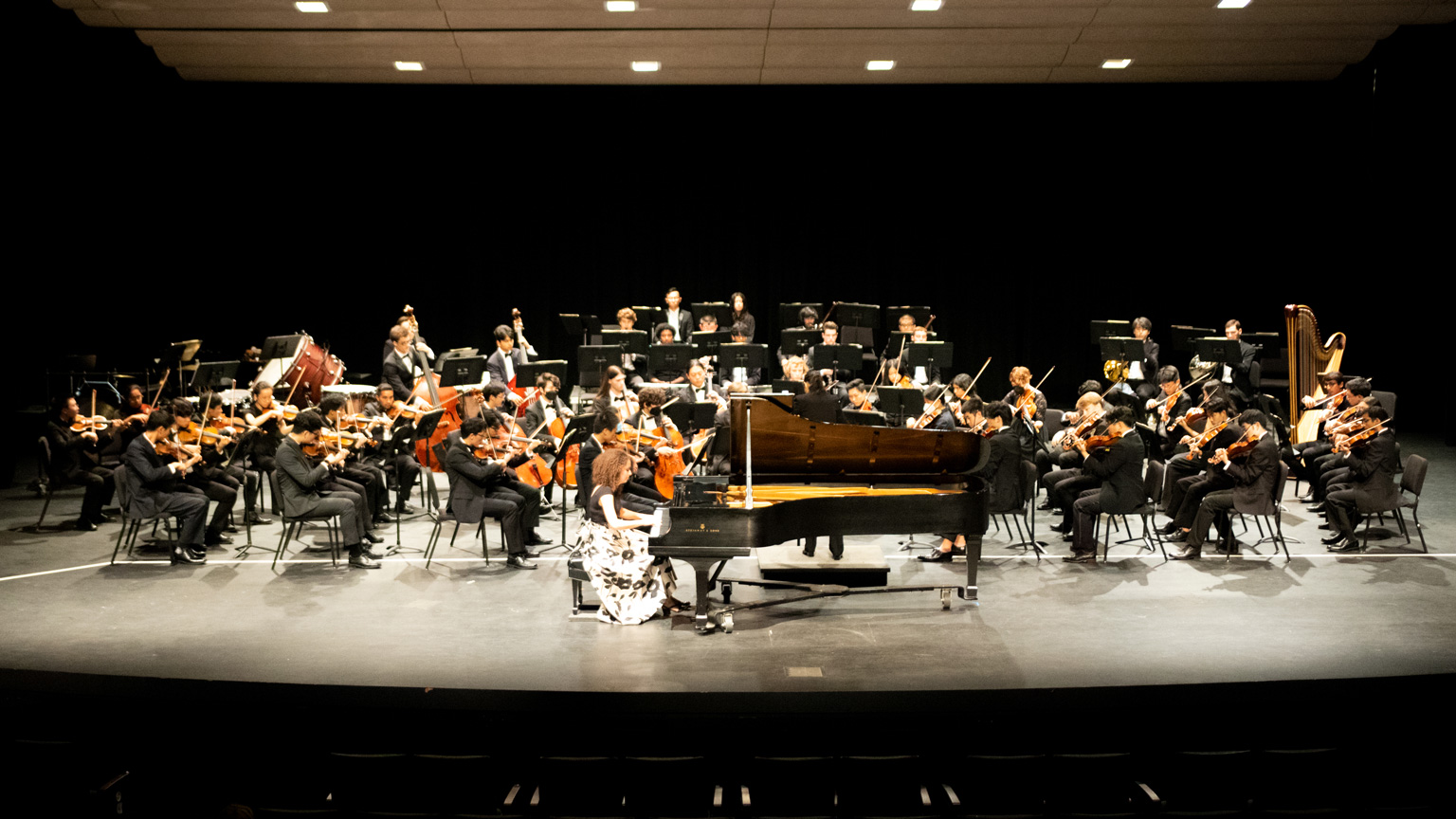 Wide view of symphony orchestra with solo pianist in front