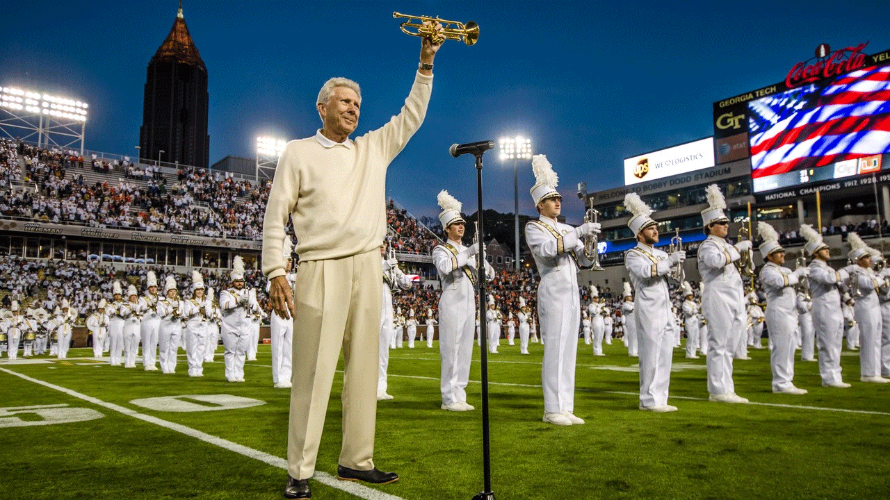 Cecil Welch holding up his trumpet on field with Georgia Tech Marching Band