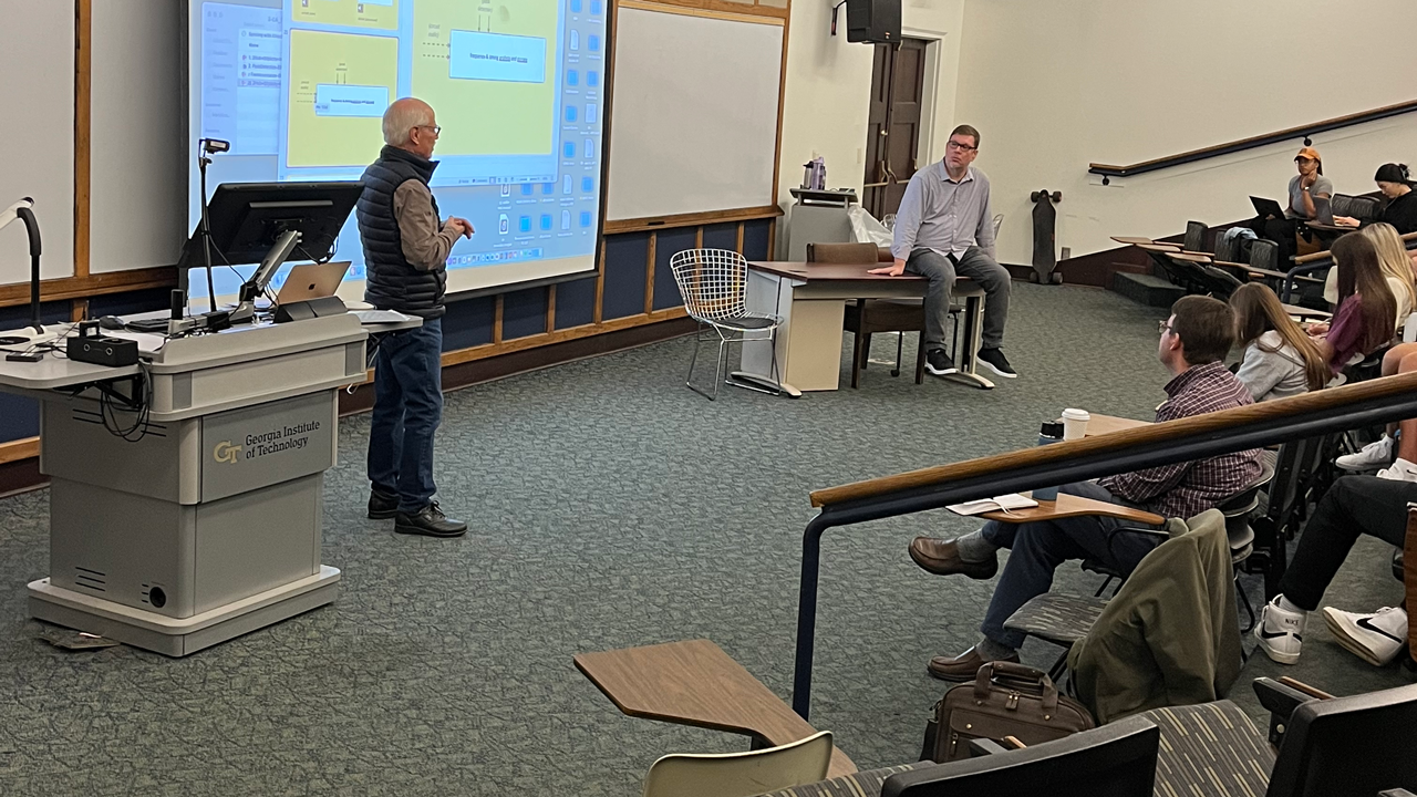 John Bischoff and Jeff Albert in front of a class full of students