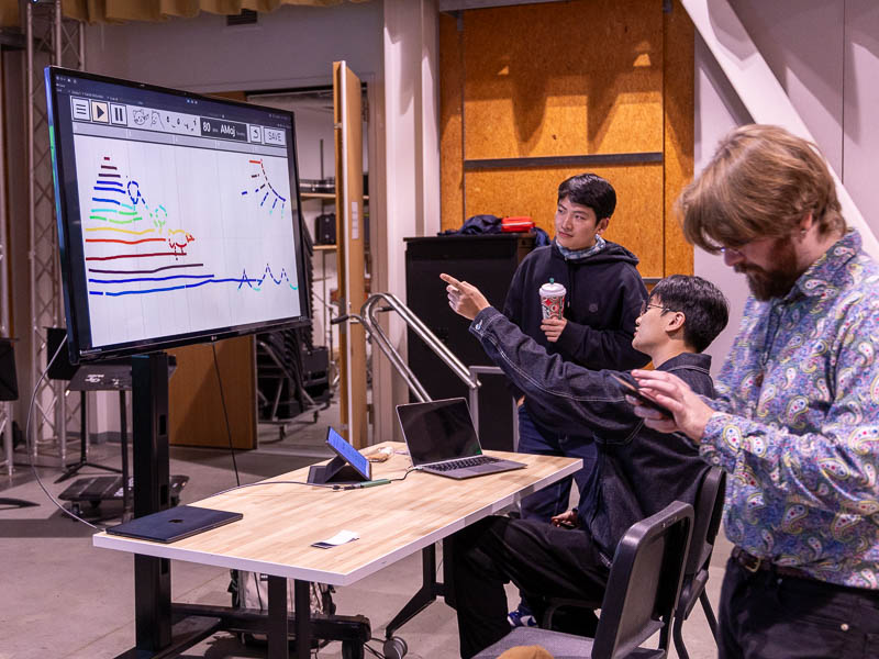 Students testing an interactive display that generates sound based on drawn scenes
